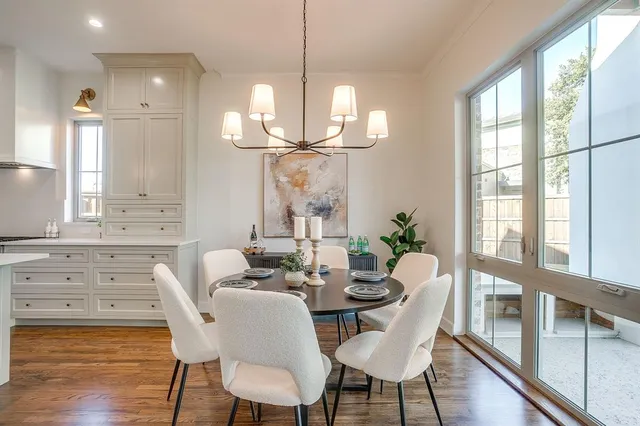 a kitchen with kitchen island a dining table chairs and white cabinets
