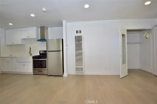 a kitchen with stainless steel appliances a refrigerator and white cabinets
