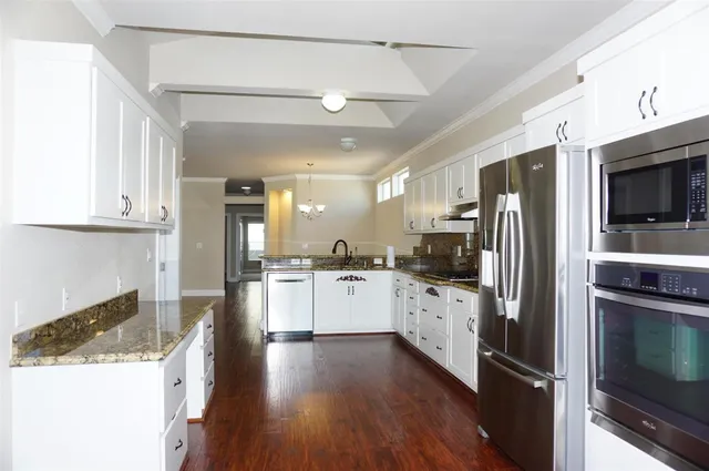 a kitchen with a sink wooden floor and stainless steel appliances