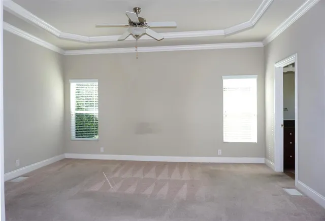 an empty room with windows and fan