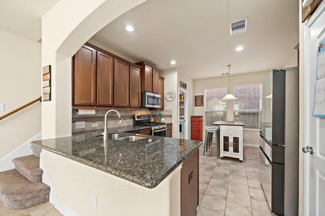 a kitchen with kitchen island granite countertop a sink counter top space appliances and cabinets