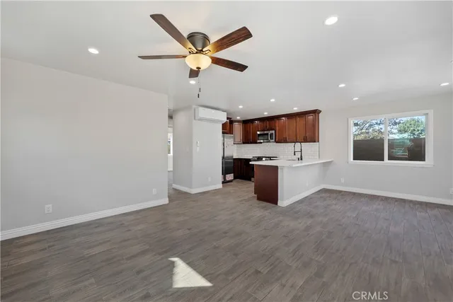 an empty room with wooden floor chandelier fan and windows