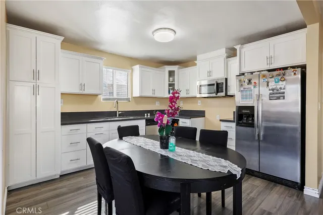 a kitchen with stainless steel appliances granite countertop a dining table chairs and a refrigerator