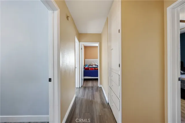 a view of a hallway with wooden floor and a bathroom
