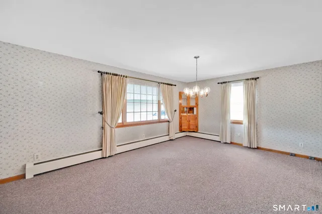 an empty room with windows and chandelier fan