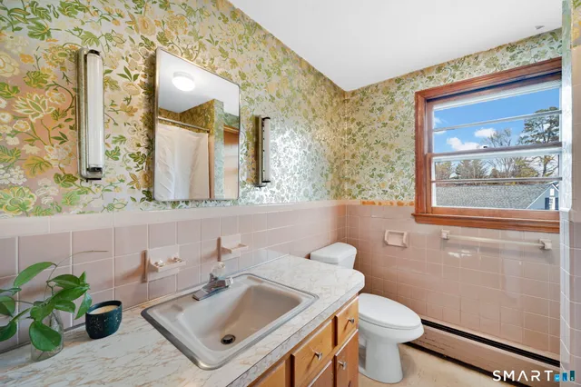 a bathroom with a sink mirror toilet and next to a window