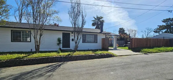 a view of a house with a small yard and wooden fence