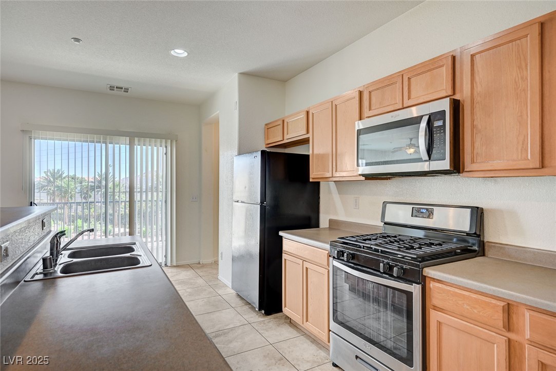 4437 Dover Straight Street, Unit 208 Las Vegas, NV 89115 - Photo 11 of 33 Kitchen featuring stainless steel appliances, light brown cabinets, light tile patterned floors, recessed lighting, and light countertops