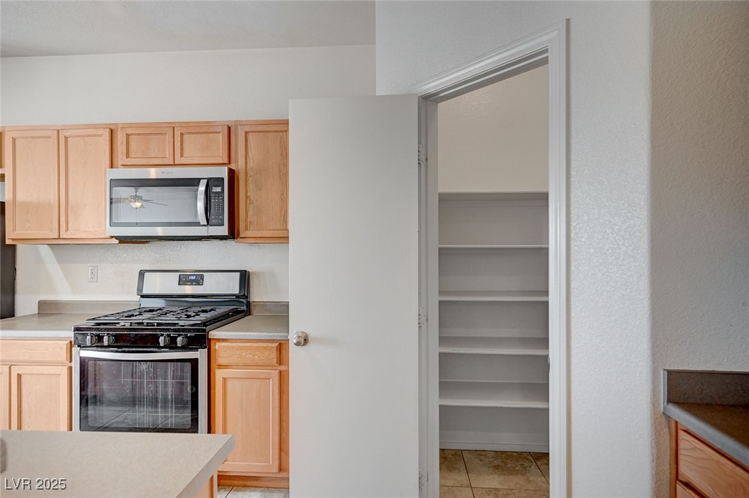 4437 Dover Straight Street, Unit 208 Las Vegas, NV 89115 - Photo 12 of 33 Kitchen featuring stainless steel appliances, light brown cabinetry, light countertops, and light tile patterned floors