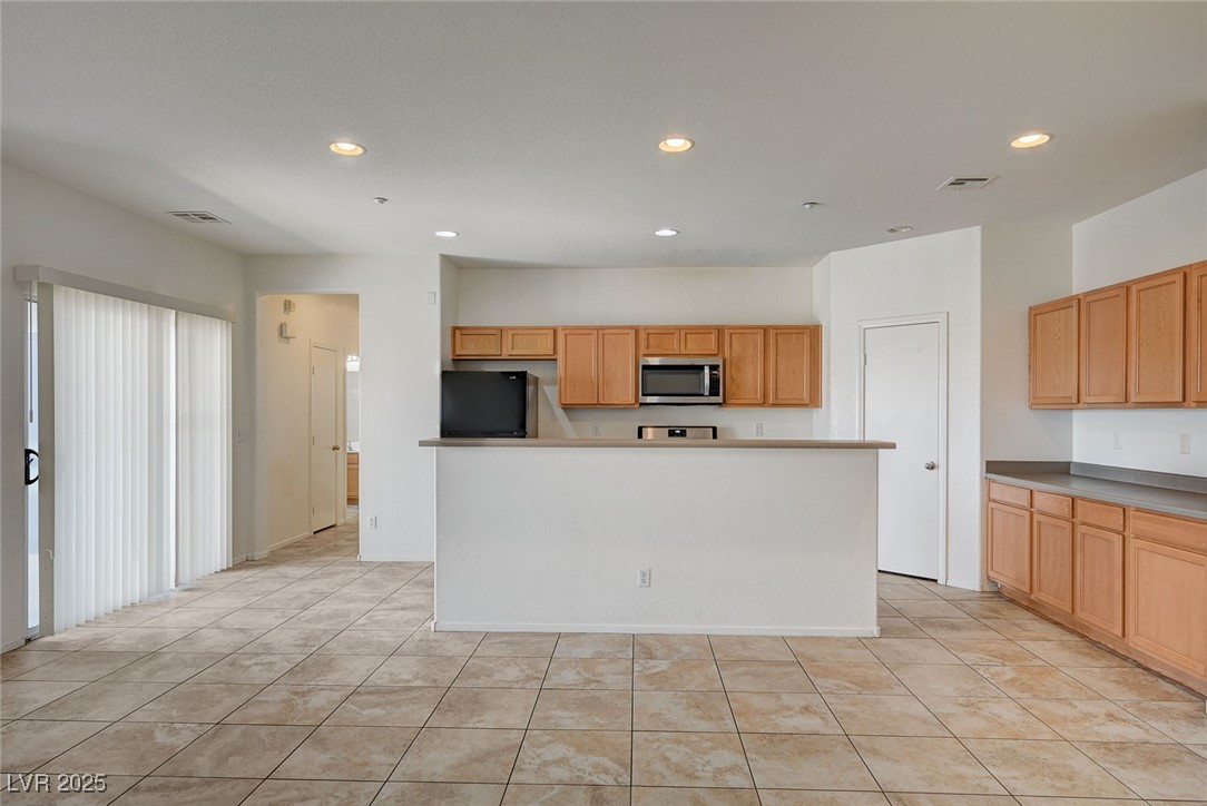4437 Dover Straight Street, Unit 208 Las Vegas, NV 89115 - Photo 6 of 33 Kitchen with recessed lighting, a kitchen island, fridge, stainless steel microwave, and light tile patterned floors