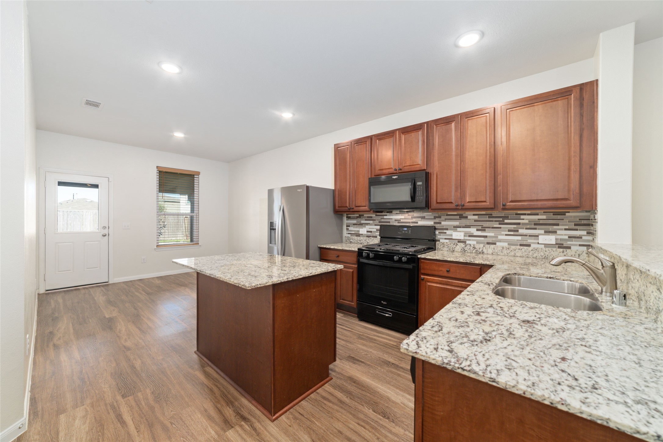 7227 Hobby Wind Ridge Drive Houston, TX 77075 - Photo 13 of 25 a kitchen with stainless steel appliances granite countertop a stove top oven a sink dishwasher and wooden cabinets with wooden floor
