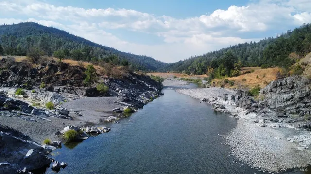 a view of a lake with a yard and large trees