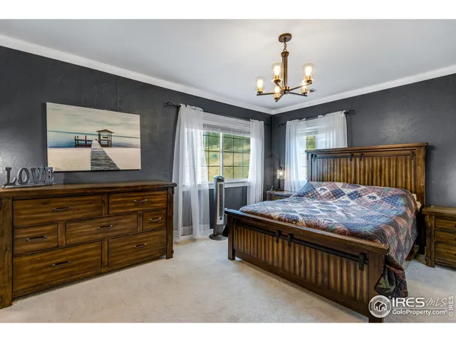 a bedroom with a large bed a chandelier and dresser