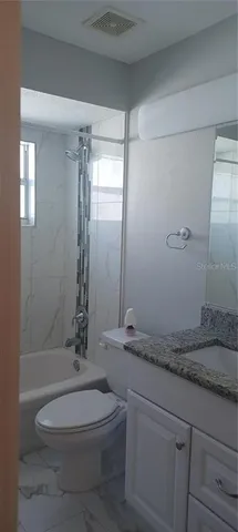 a bathroom with a granite countertop bathtub sink vanity mirror and toilet