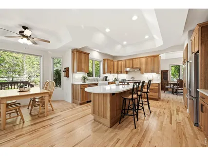 a dining hall with stainless steel appliances a dining table wooden floor and a large window