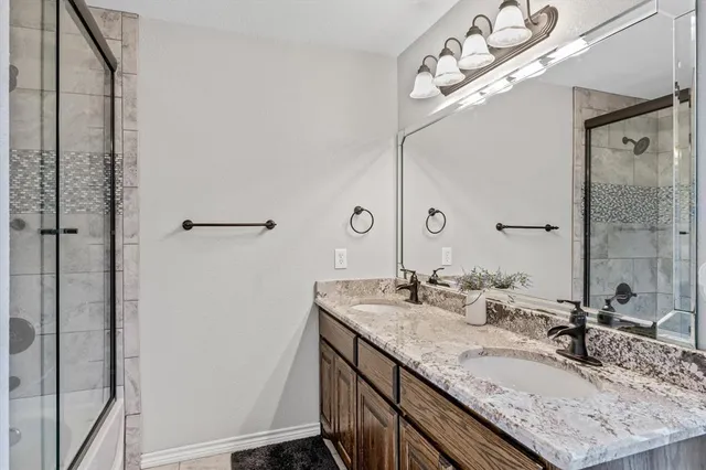 a bathroom with a granite countertop sink a mirror and shower