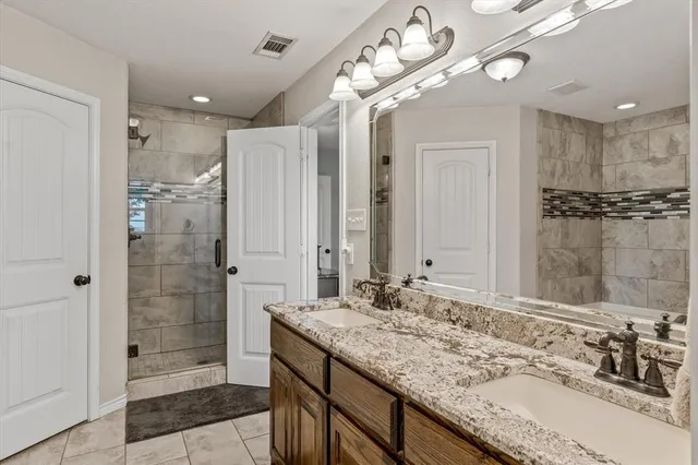 a bathroom with a granite countertop sink a large mirror and a shower