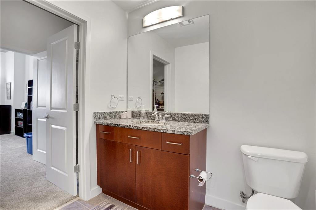 250 Pharr Road Northeast, Unit 2005 Atlanta, GA 30305 - Photo 21 of 49 a bathroom with a granite countertop sink a toilet and a mirror