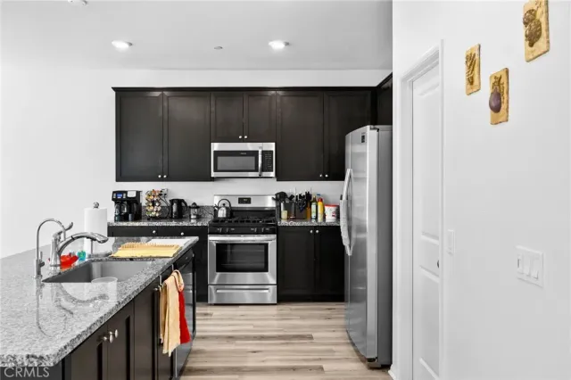 a kitchen with stainless steel appliances granite countertop a sink stove and wooden floor