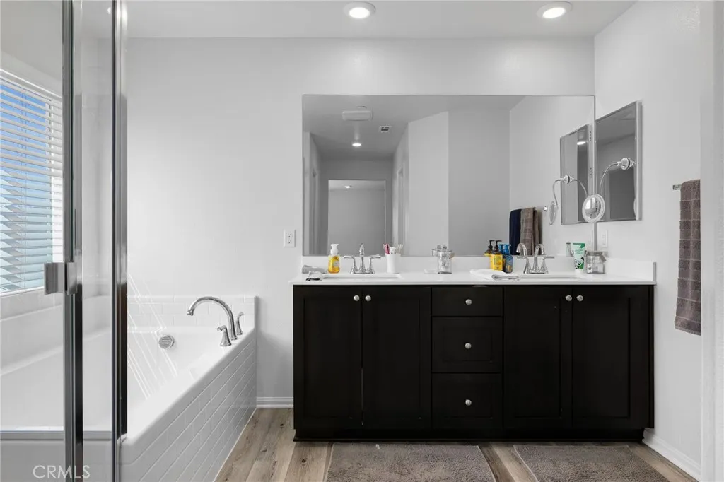12487 Sunset Road Victorville, CA 92392 - Photo 32 of 44 a bathroom with a double vanity sink a tub and mirror