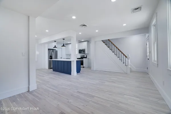 a living room with stainless steel appliances kitchen island wooden floors and fireplace