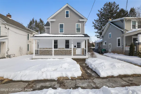 a front view of a house with a yard covered in snow