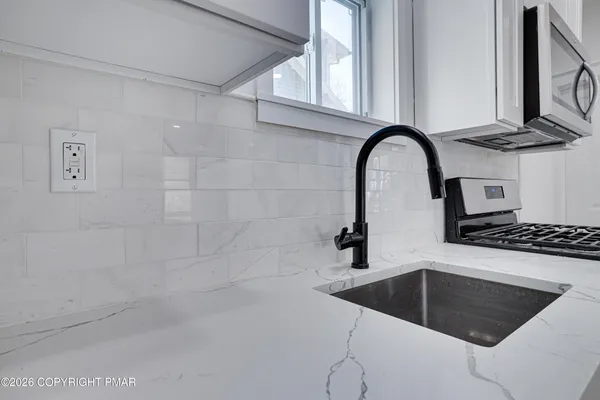 a large kitchen with stainless steel appliances a refrigerator and a chandelier