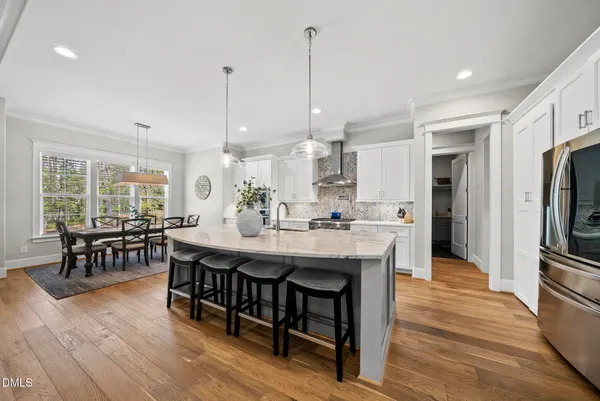 a dining hall with stainless steel appliances granite countertop wooden floor a dining table and chairs