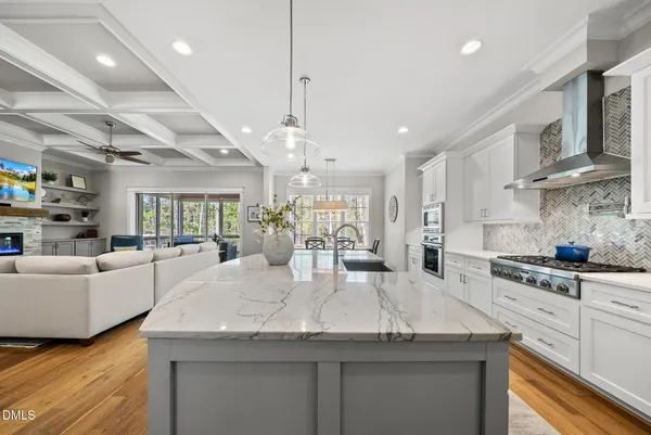 a kitchen with stainless steel appliances granite countertop a stove a sink a refrigerator and white cabinets with wooden floor