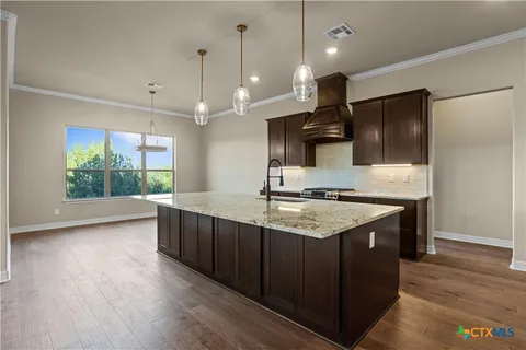 a kitchen with stainless steel appliances granite countertop a sink a stove and a wooden floors