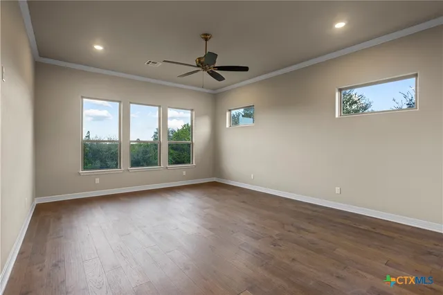 an empty room with wooden floor fan and windows