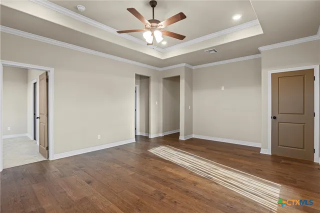 an empty room with wooden floor and ceiling fan