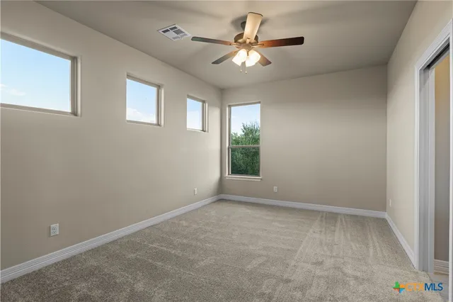 an empty room with windows and fan