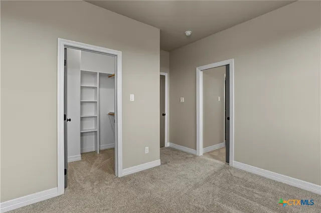 an empty room with closet and a hallway