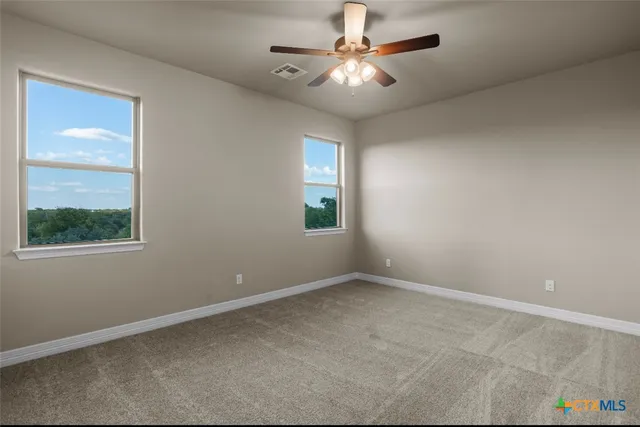 an empty room with windows and fan