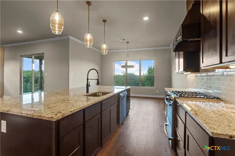 a kitchen with granite countertop a sink stove and cabinets