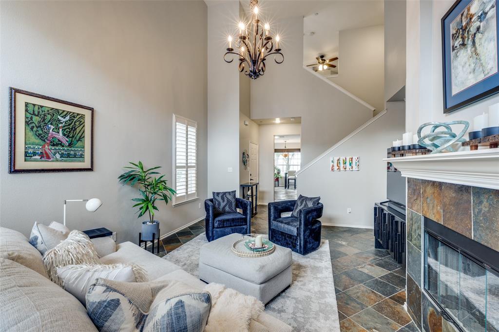 3124 Twist Trail Plano, TX 75093 - Photo 1 of 24 Living area with a notable chandelier, stone tile floors, a fireplace, a towering ceiling, and baseboards