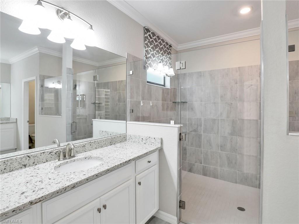 17528 Ashcomb Way Estero, FL 33928 - Photo 15 of 42 a bathroom with a granite countertop sink a mirror a shower and a bathtub