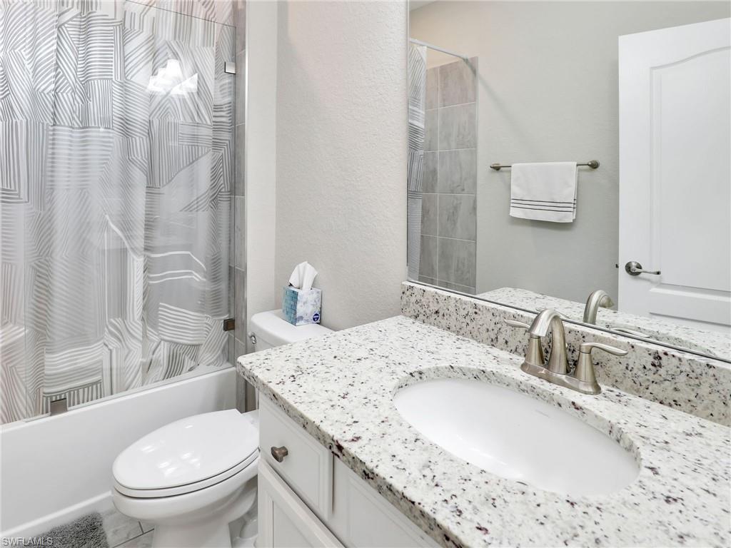 17528 Ashcomb Way Estero, FL 33928 - Photo 20 of 42 a bathroom with a granite countertop sink a toilet and shower