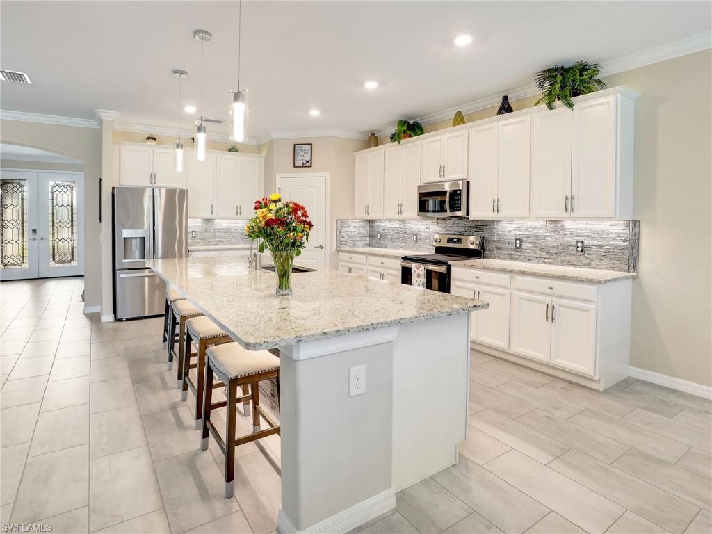17528 Ashcomb Way Estero, FL 33928 - Photo 3 of 42 a kitchen with stainless steel appliances kitchen island granite countertop a sink and cabinets