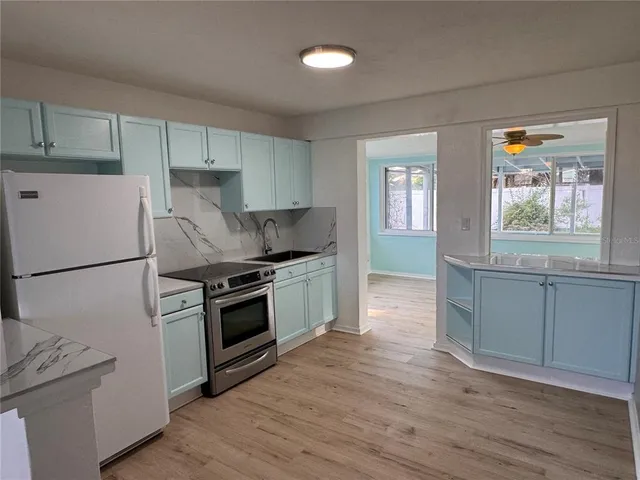 a kitchen with granite countertop a refrigerator stove and sink