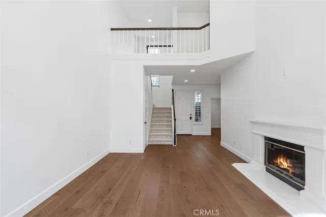 an empty room with wooden floor fireplace and windows