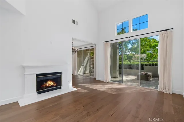 a view of an empty room with wooden floor fireplace and a window