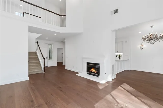 a view of an empty room with wooden floor fireplace and a window