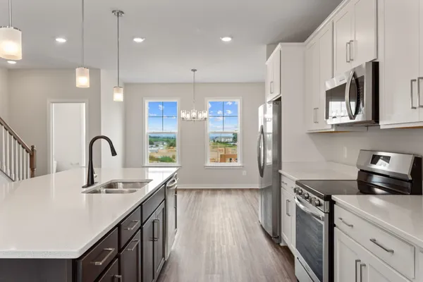 a kitchen with kitchen island granite countertop a stove a sink a refrigerator wooden floor and cabinets