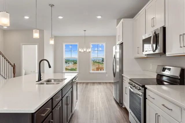 a kitchen with kitchen island granite countertop a stove a sink a refrigerator wooden floor and cabinets