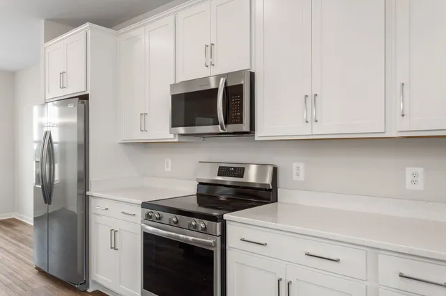 a kitchen with stainless steel appliances granite countertop white cabinets and a stove a refrigerator with white cabinets