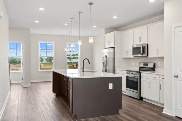 a kitchen with stainless steel appliances granite countertop a stove a sink dishwasher a refrigerator white cabinets and wooden floor next to a window