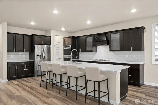 a kitchen with stainless steel appliances kitchen island granite countertop a refrigerator a stove a sink a dining table and chairs