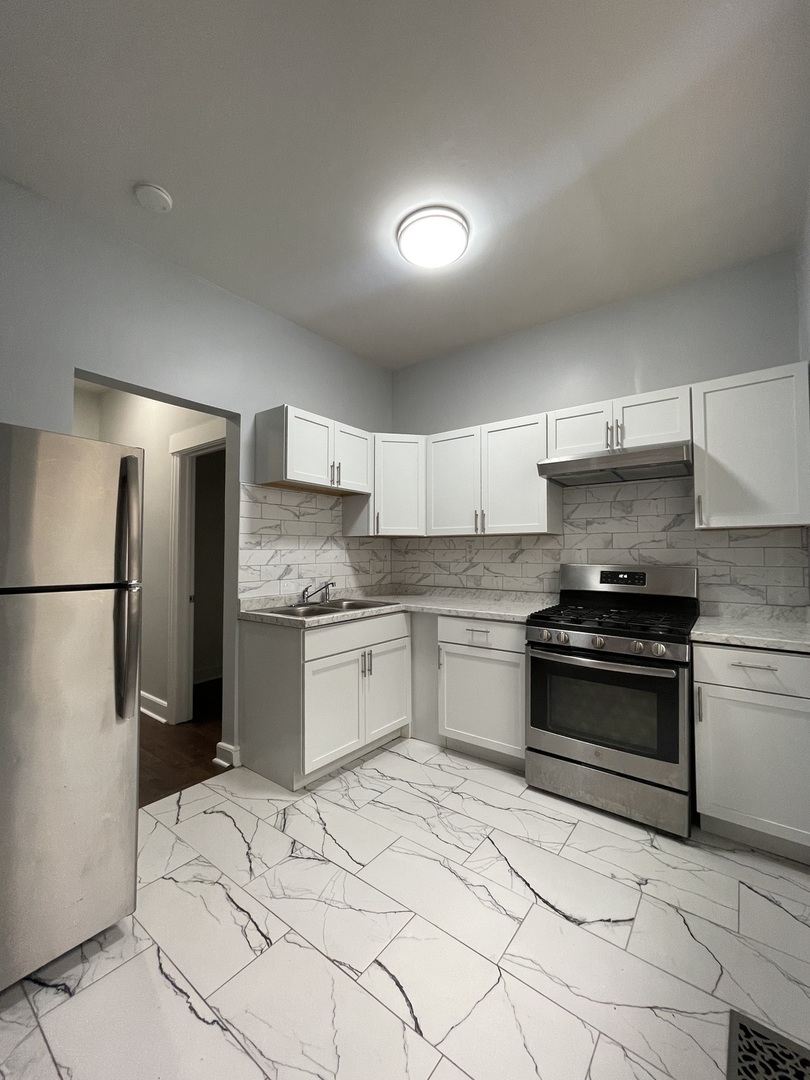 916 West 68th Street, Unit 1W Chicago, IL 60621 - Photo 8 of 8 a kitchen with granite countertop a stove a sink and a refrigerator